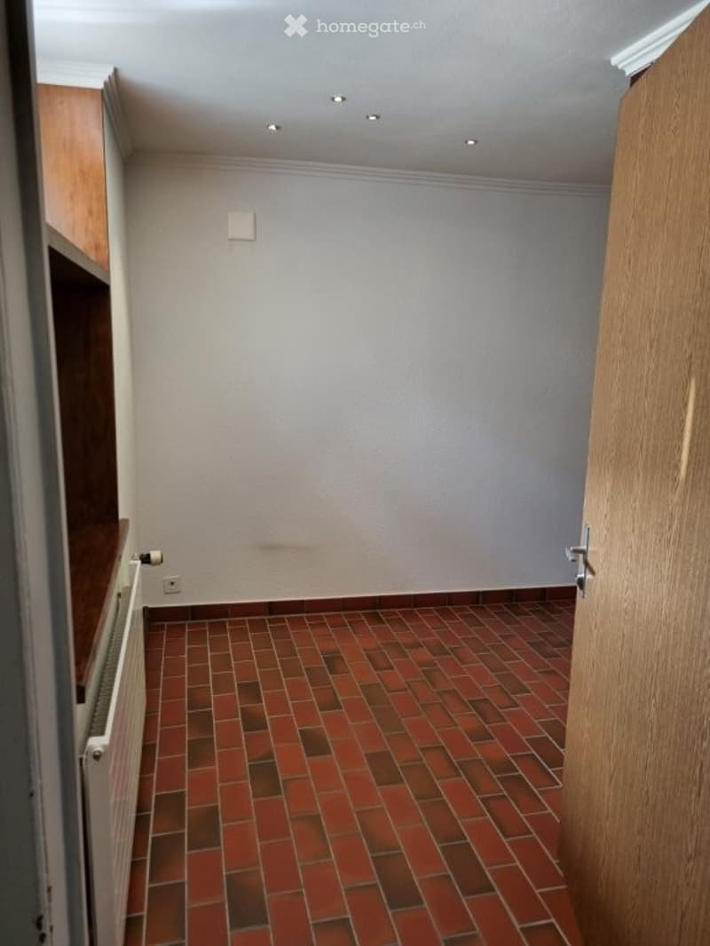 empty room, red brick floor, white walls, wooden door, wooden shelf, radiator