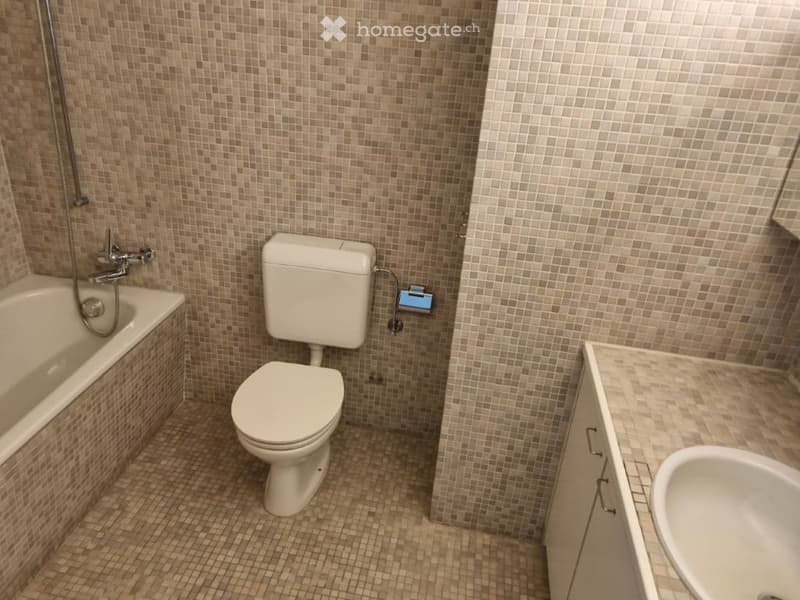 Bathroom with bathtub, toilet, sink, and tiled walls and floor.