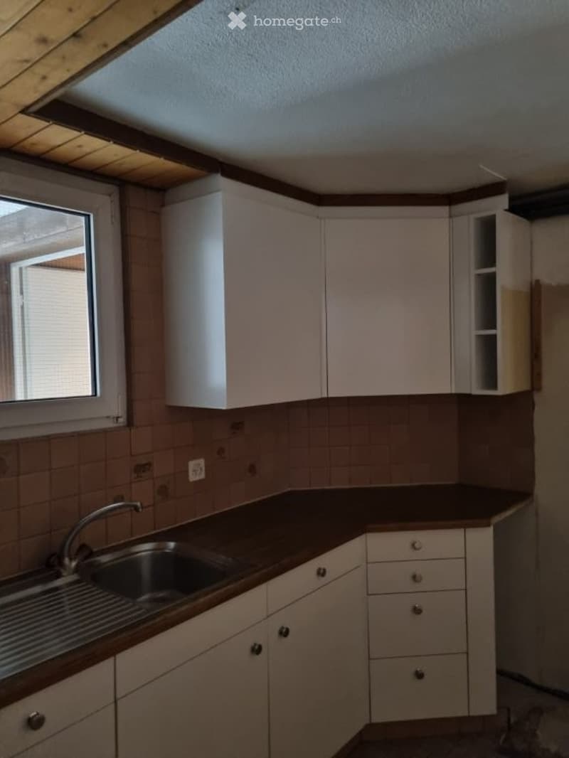 kitchen with white cabinets, brown countertop, stainless steel sink, faucet, window, tiled wall