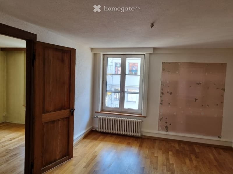 empty room, wooden floor, white walls, window, radiator, wooden door
