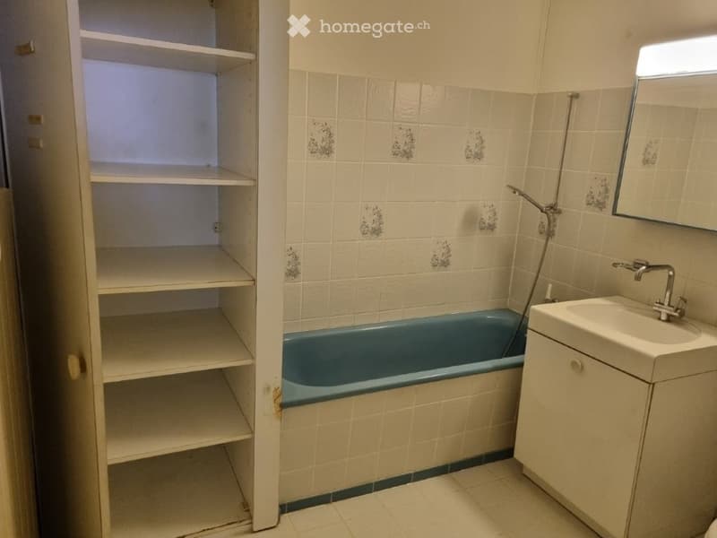 Bathroom with bathtub, sink, mirror, and shelves