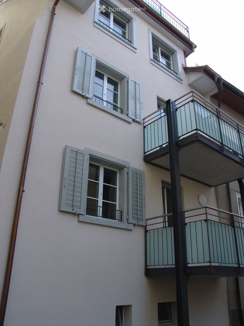 white building, multiple windows, balconies, metal railings
