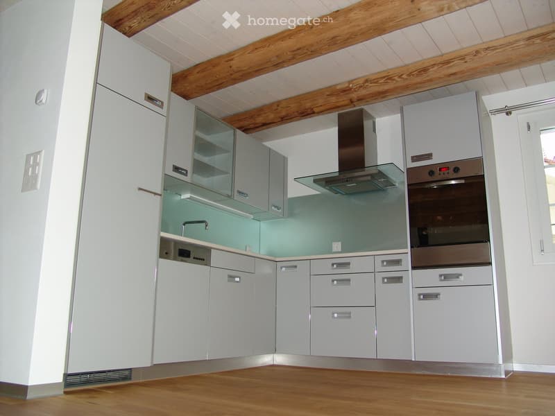 modern kitchen with white cabinets, wooden beams, stainless steel appliances, green backsplash, wooden floor