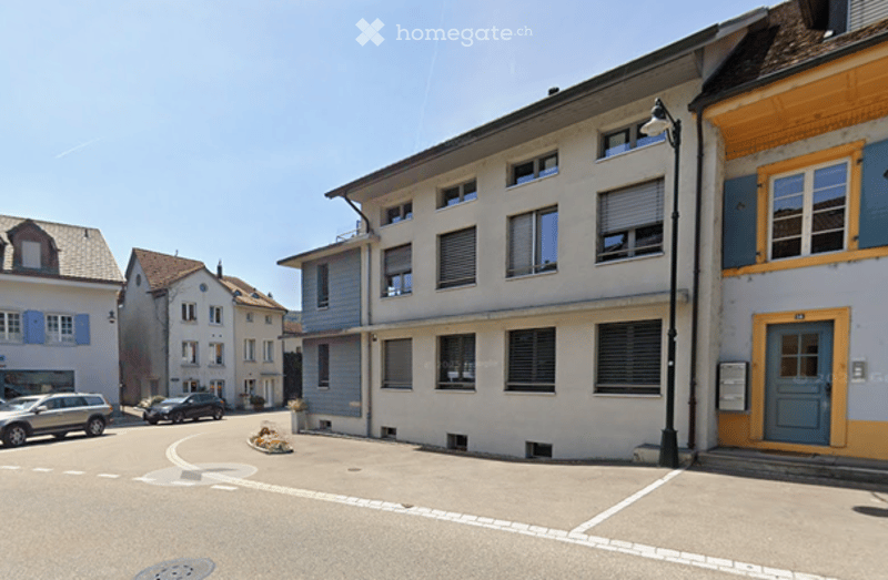 3 story building, beige and blue facade, multiple windows, street light, parking lot
