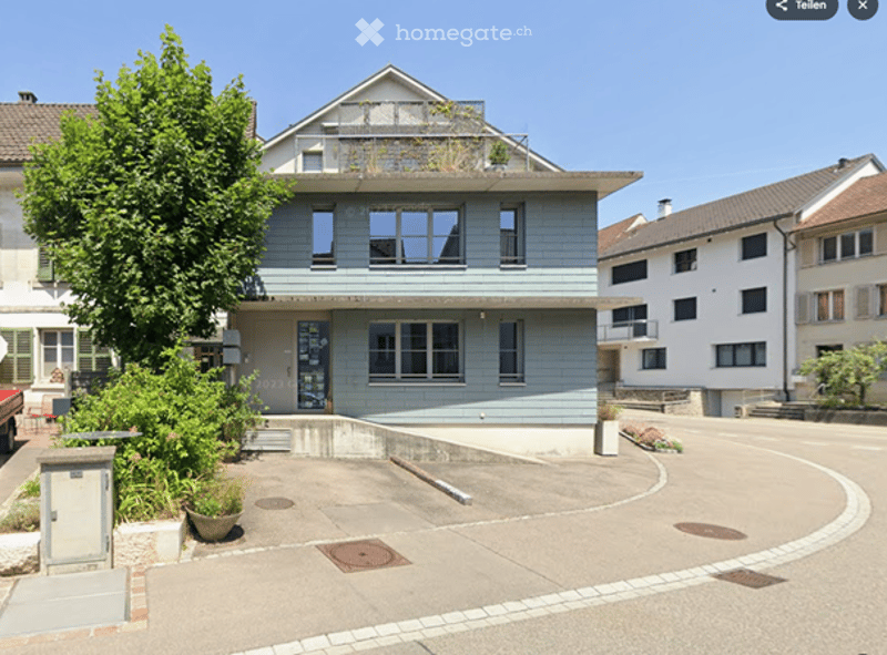 2 story house, blue exterior, white windows, raised ground floor, terrace, parking area