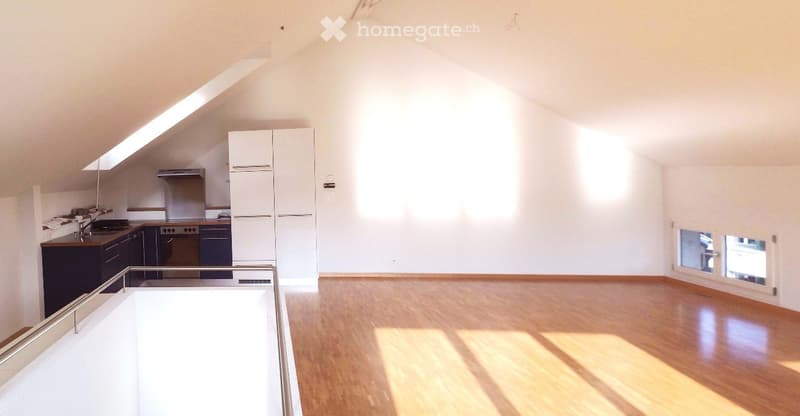 Empty room, wooden floor, white walls, kitchen area with sink, cabinets, and stove, windows, and a balcony