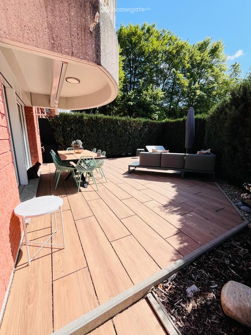 Wooden deck with outdoor dining table and chairs, lounge sofa, and a closed umbrella