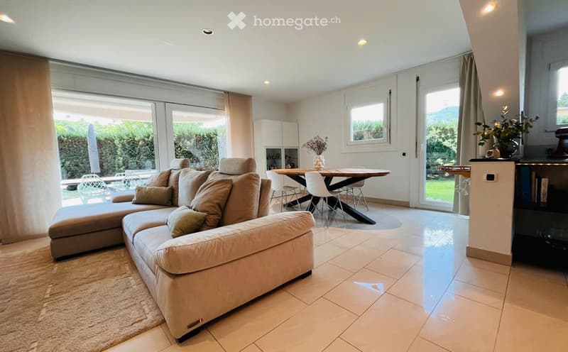 modern living room with large windows, beige sofa, wooden table, white chairs, beige carpet, white tiles, white cabinets, plants