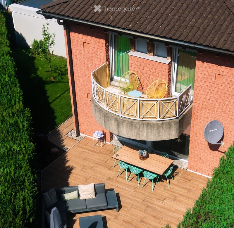 Wooden deck with a grey sofa, small table, and chairs. A round balcony with two yellow fans and a small table. Satellite dish on the wall.