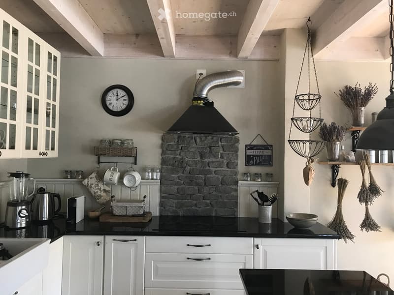 kitchen with fireplace, white cabinets, black countertops, hanging basket with lavender, basket of utensils, a clock