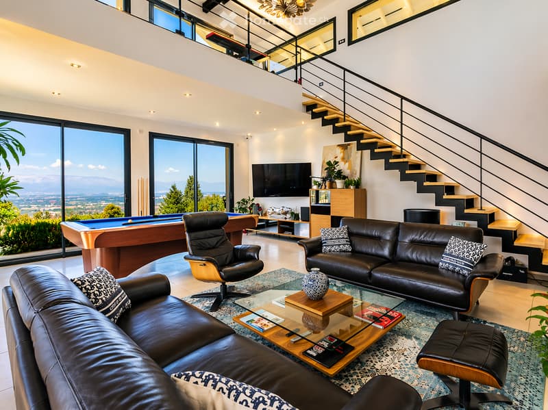 modern design, large windows, leather couches, glass coffee table, pool table, television, staircase