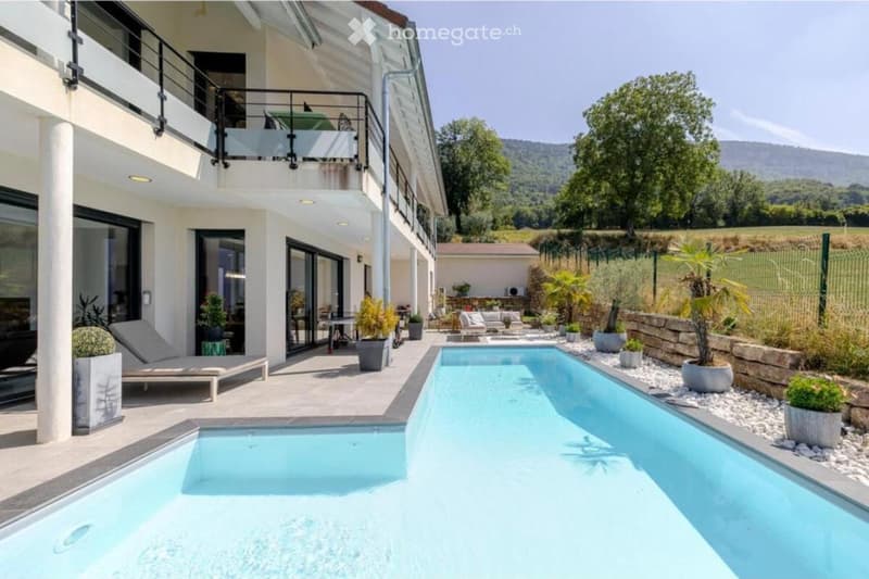 Modern house with swimming pool, balcony, lounge chairs, potted plants, and a view of the mountains