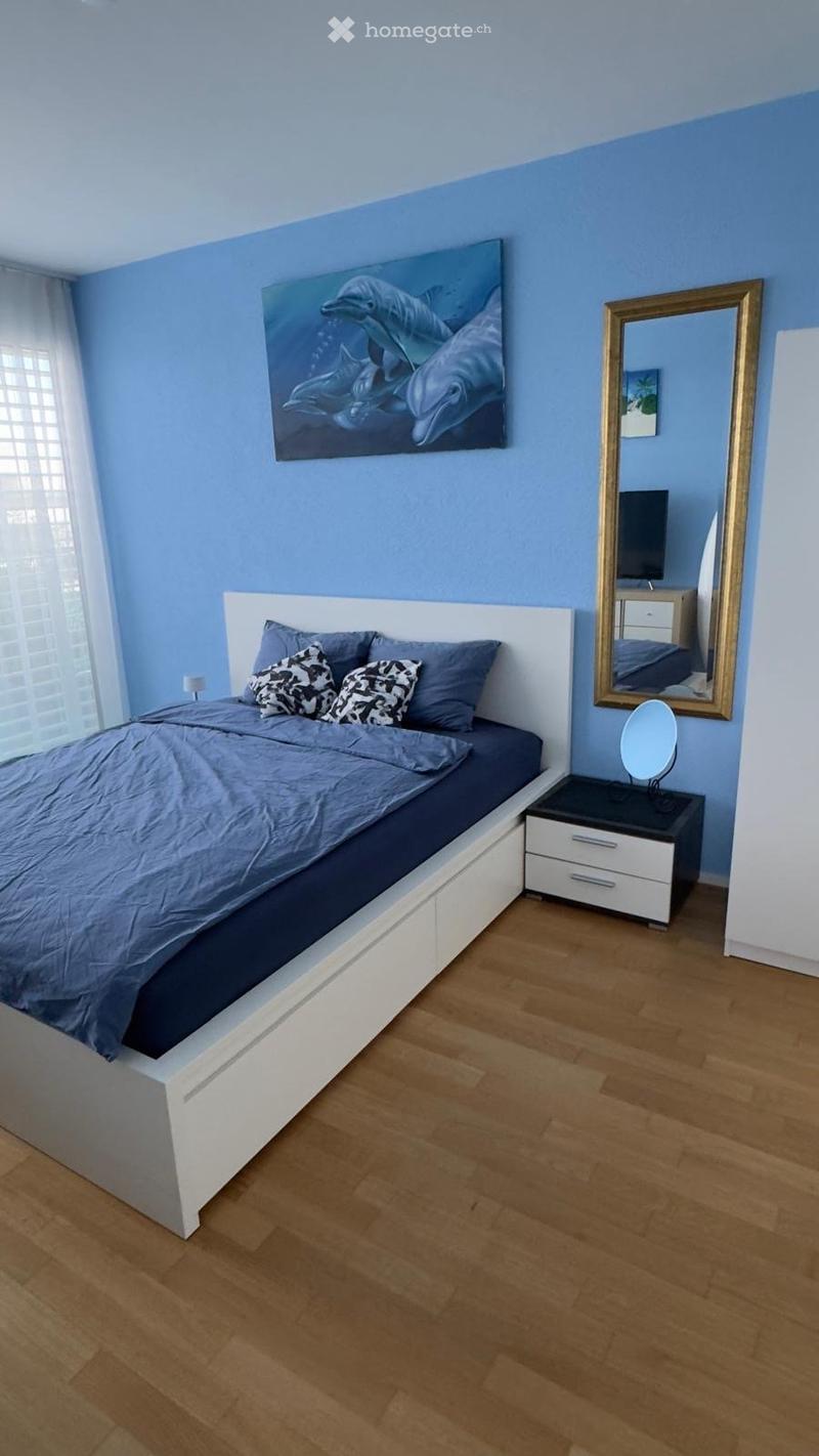 Bedroom with blue walls, white bed, nightstand, mirror, dolphin painting, wooden floor