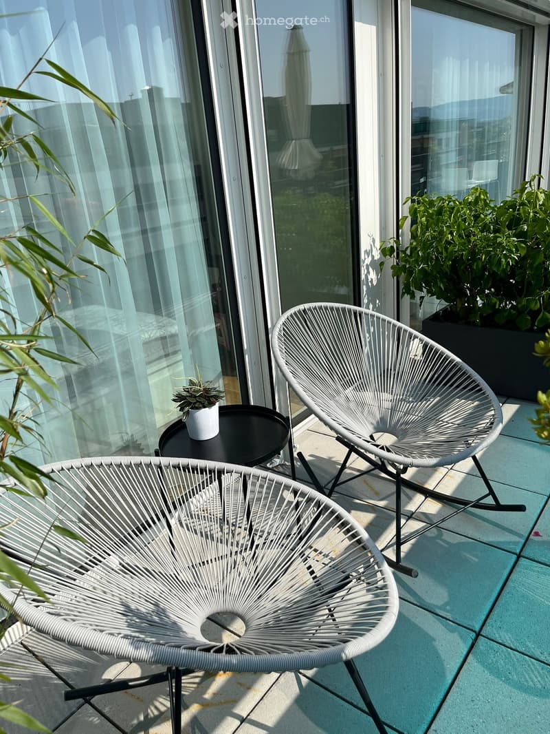Balcony with two chairs, table, plant, and glass doors