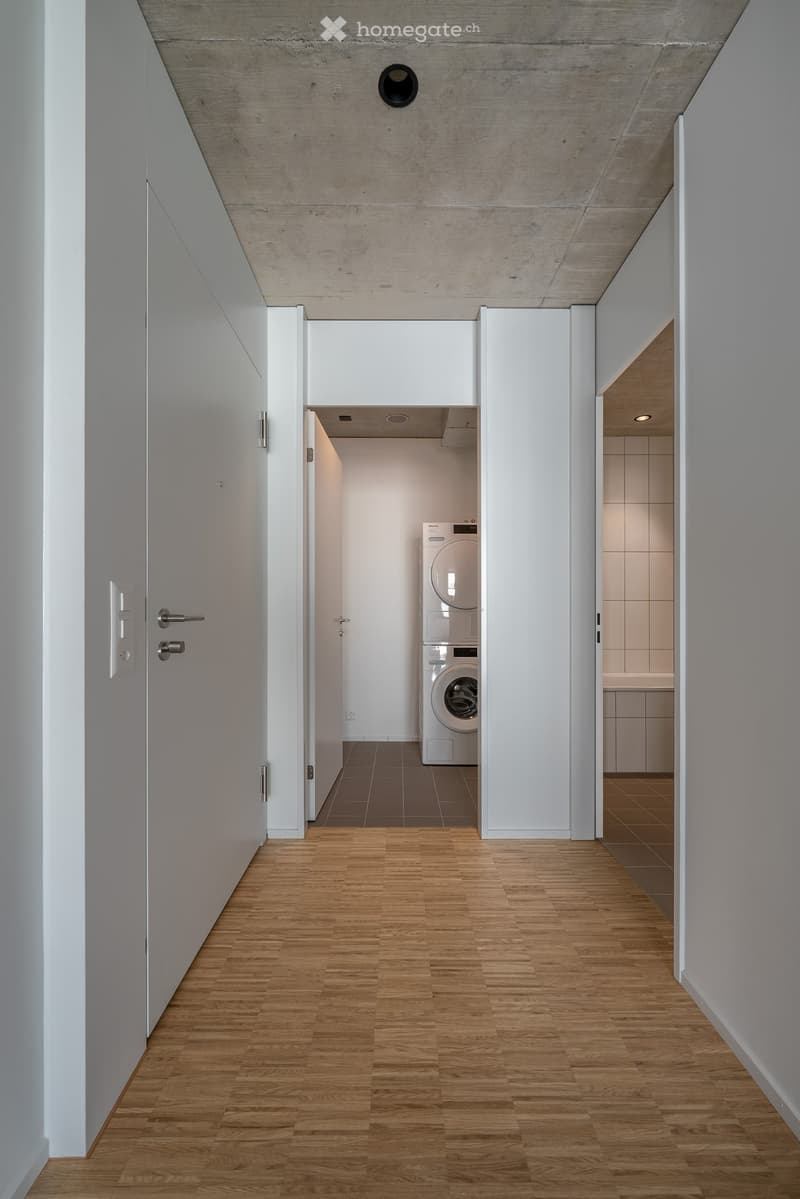 wooden floor, white walls, open door leading to washer and dryer