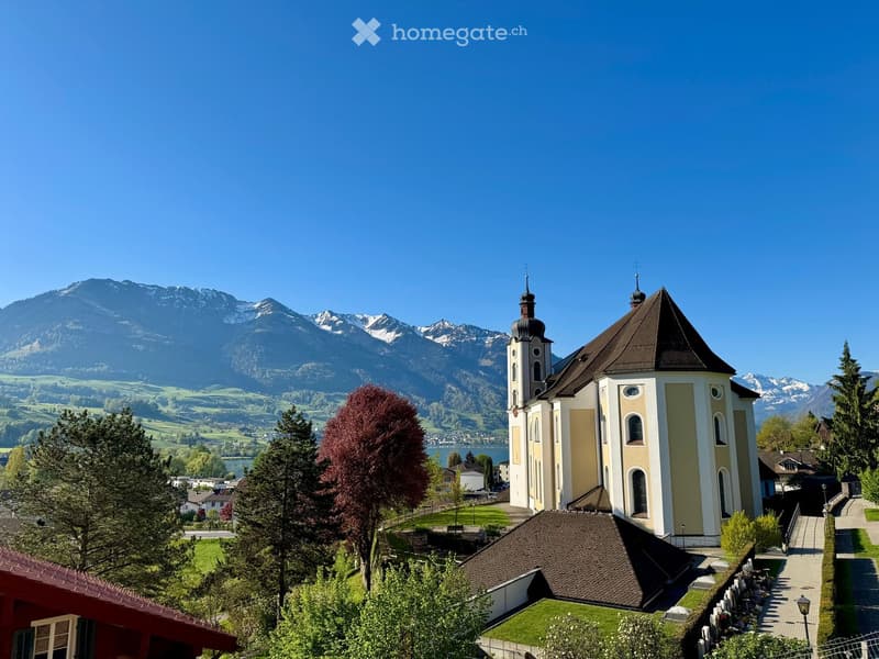 Church with two towers, brown roof, surrounded by trees and mountains