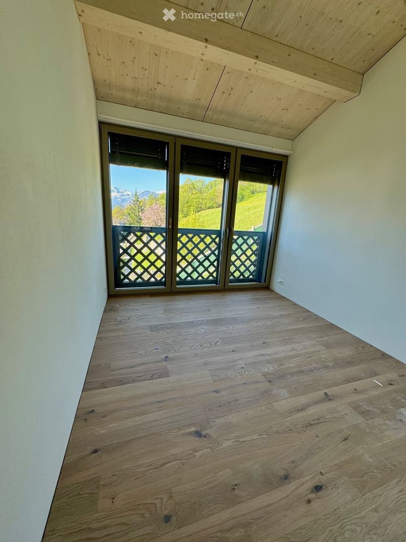 empty room, wooden floor, white walls, large glass doors leading to balcony, balcony with metal railing, scenic view of mountains and greenery