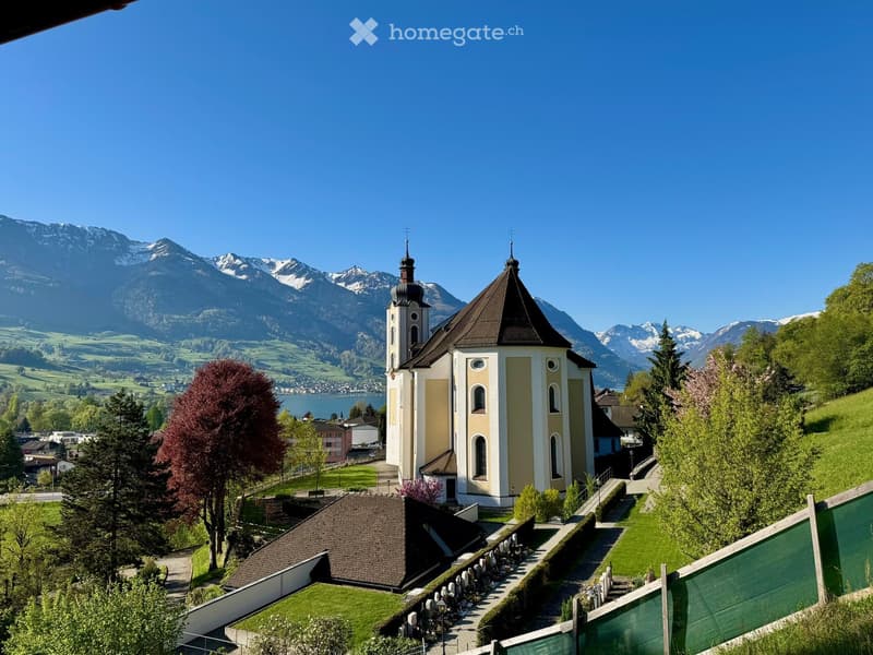 Church with two towers, brown roof, surrounded by trees and mountains