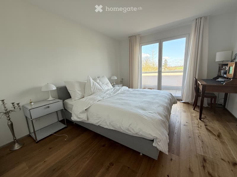 Bedroom with bed, nightstands, lamps, desk, chair, sliding glass door, wooden floor, white walls, view of the outside