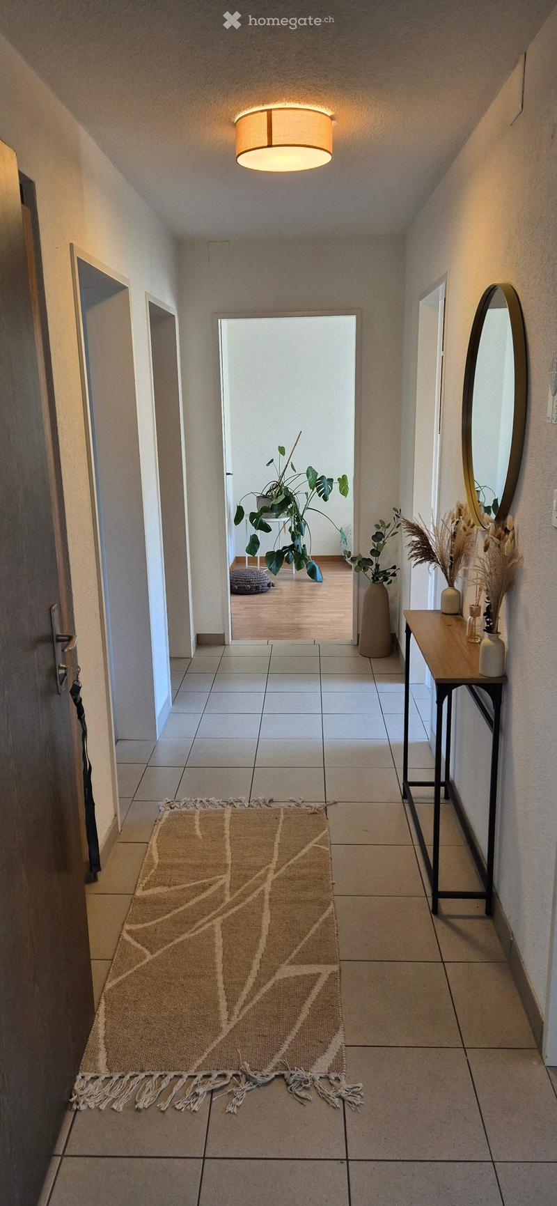 tiled floor, hallway, rug, mirror, plants, wooden table, ceiling light