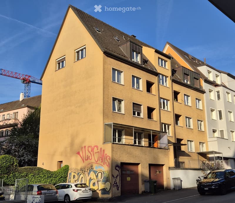 5 story building, yellow exterior, graffiti, balcony, 2 garages, 3 cars parked