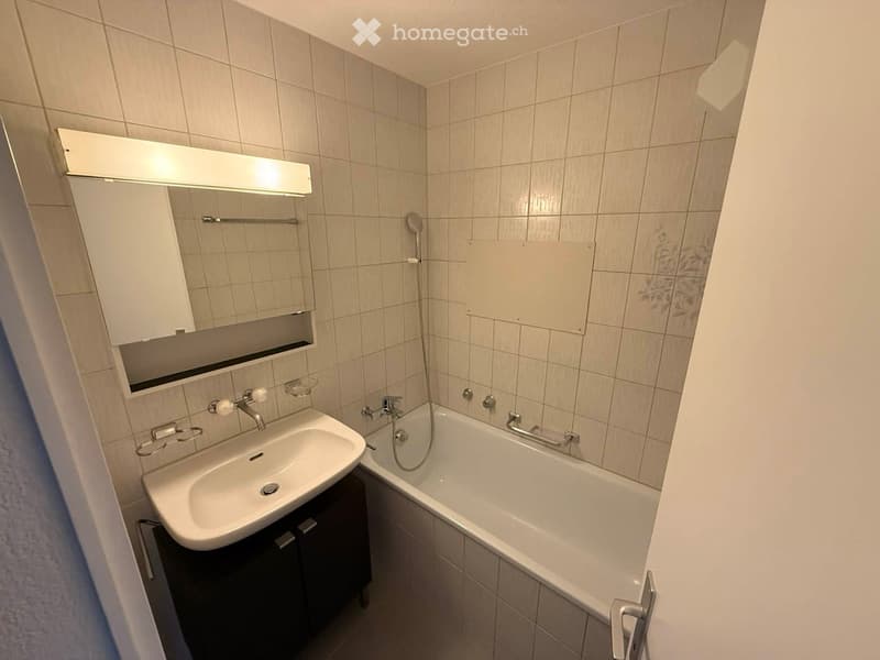 Bathroom with white tiles, bathtub, sink, mirror, and shower