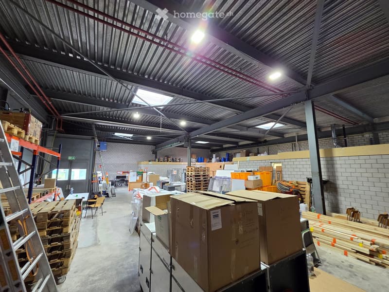 Warehouse with metal ceiling, brick walls, storage boxes, pallets, shelves, and various items