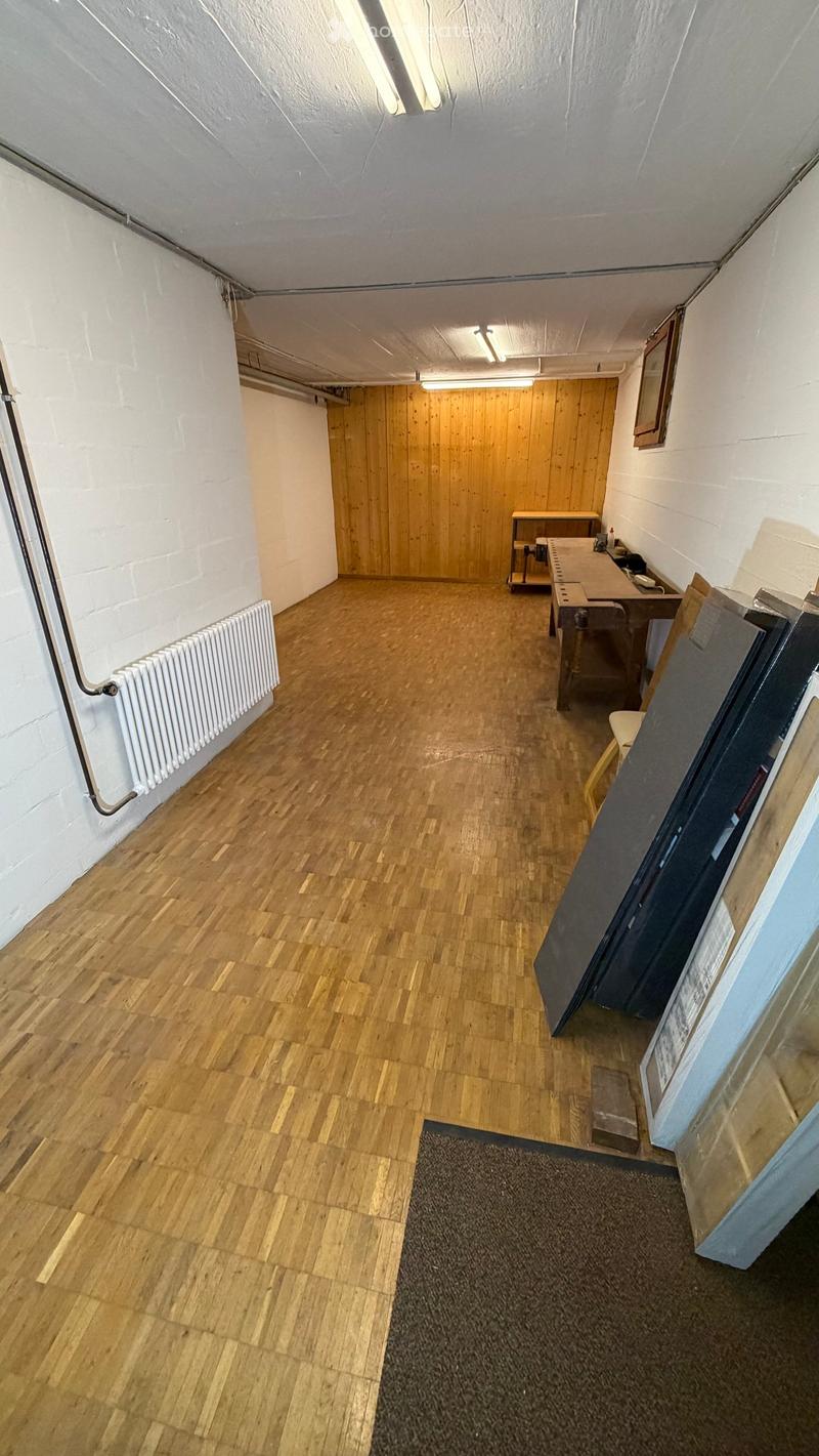 wooden floor, wooden wall, workbench, white radiator, boxes, ceiling lamp