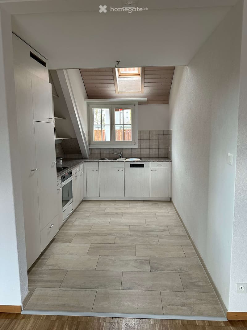 Modern kitchen with white cabinets, tiled floor, and a skylight. It includes a sink with a faucet, a dishwasher, an oven, and a microwave.