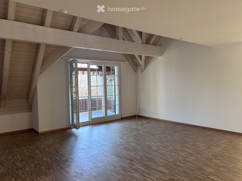 Empty room with wooden flooring, white walls, and a large sliding glass door leading to a balcony.