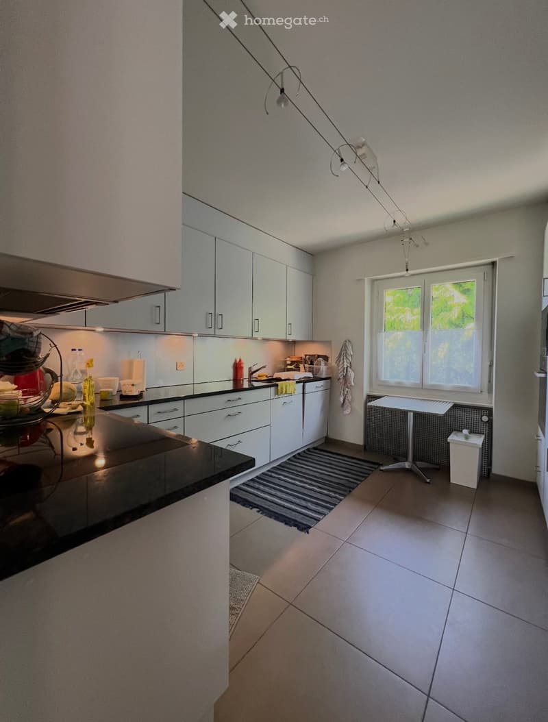modern kitchen with white cabinets, black countertops, tiled floor, window with view