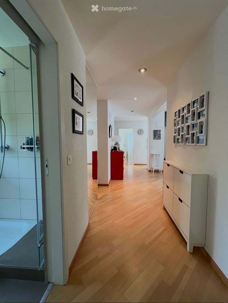 wooden floor, white walls, glass shower, white cabinet, picture frames, red cabinet, white stool, clock, lamp