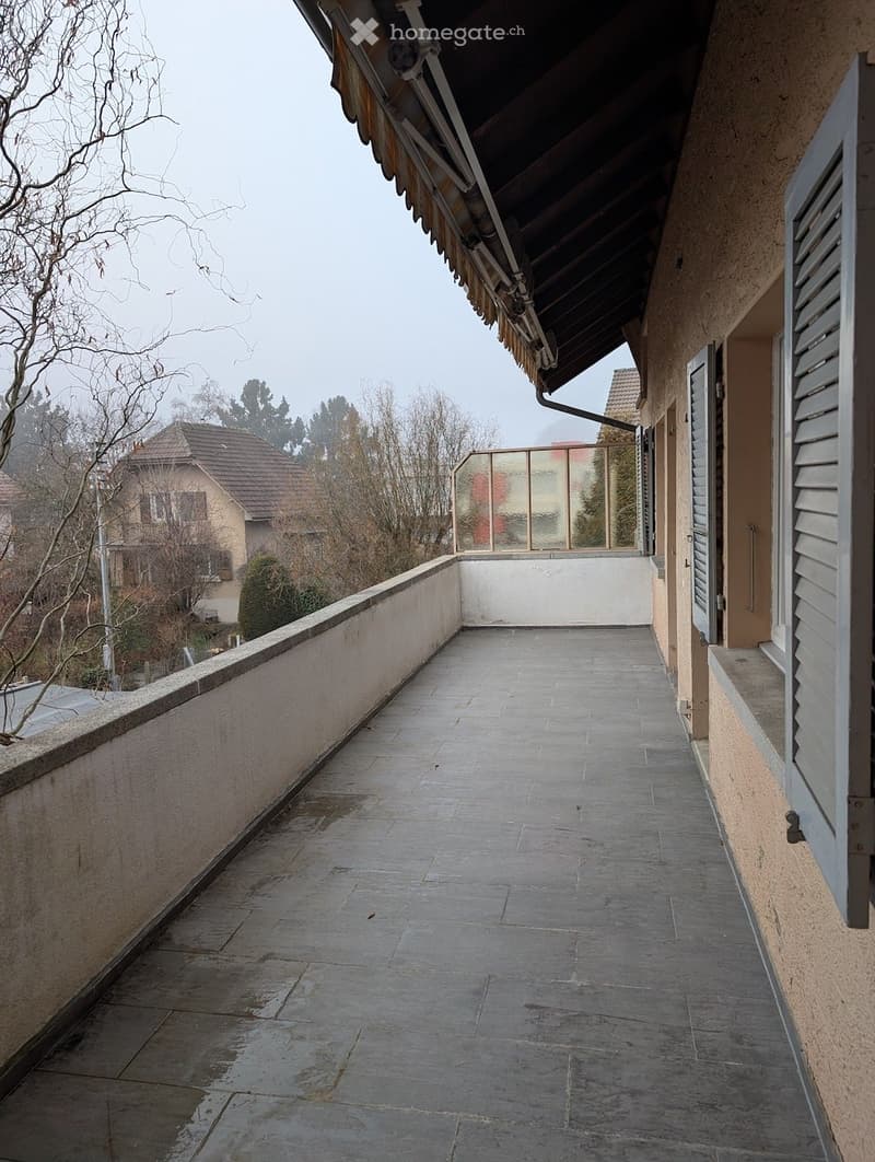 empty balcony with paved flooring, white walls, glass fence, white shutters