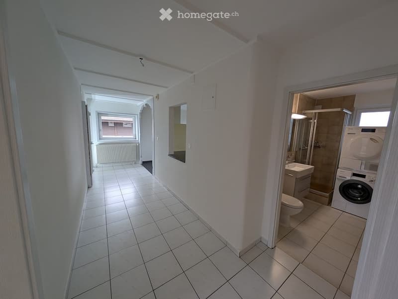 tiled floor, white walls, small hallway leading to a bathroom and laundry room