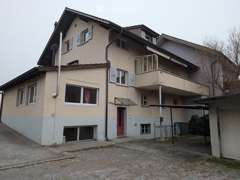 Three-story house, light brown color, multiple windows, balcony on the second floor, garage.