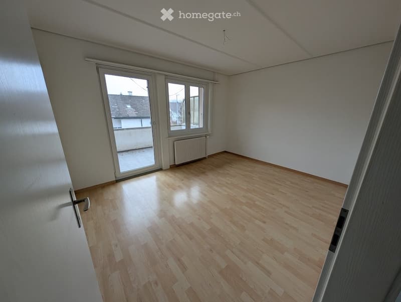 empty room with sliding glass doors and a balcony, wooden floor, white walls, radiator