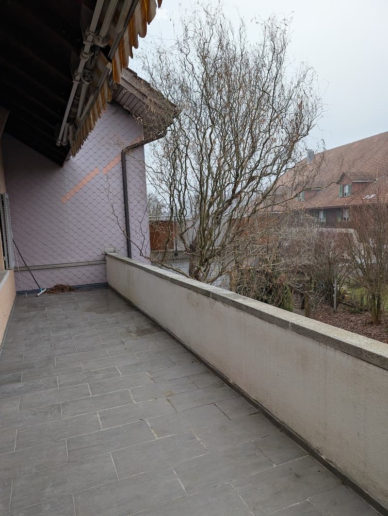 tiled floor, balcony, concrete railing, view of trees and buildings