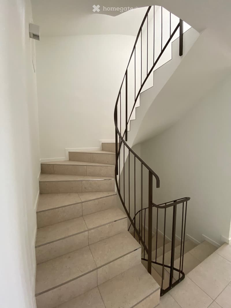 spiral staircase with tiled steps and black metal railing