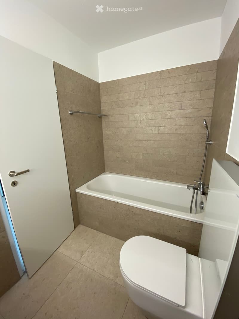 Bathroom with bathtub, toilet, and tiled walls