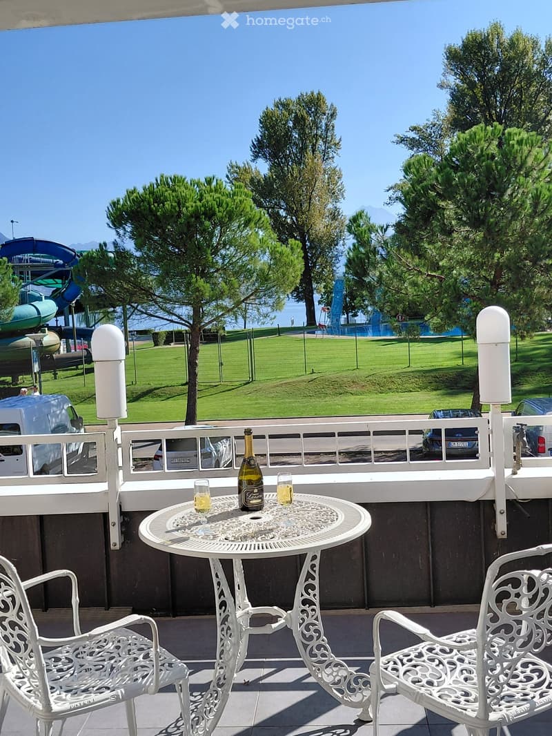 Balcony with table and chairs, bottle of wine, glasses, view of a park and water slide