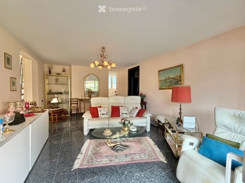 living room with white sofa, glass coffee table, pink rug, white cabinet, lamp, mirror, chandelier, paintings, and chairs