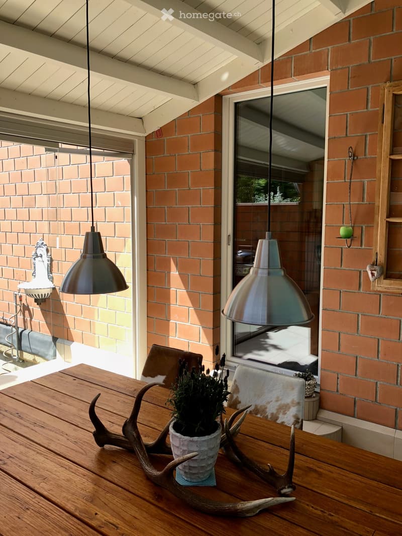 wooden table, hanging lamps, brick wall, glass door, plant, deer antlers