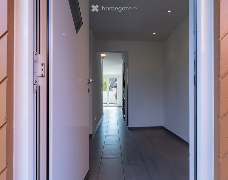 Empty hallway with white walls, wooden floor, and ceiling lights