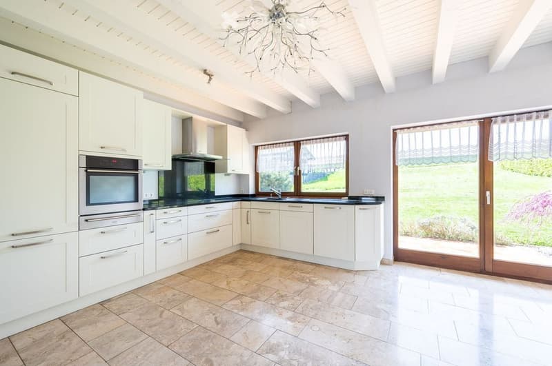 modern kitchen with white cabinets, tiled floor, large windows, oven, sink, chandelier