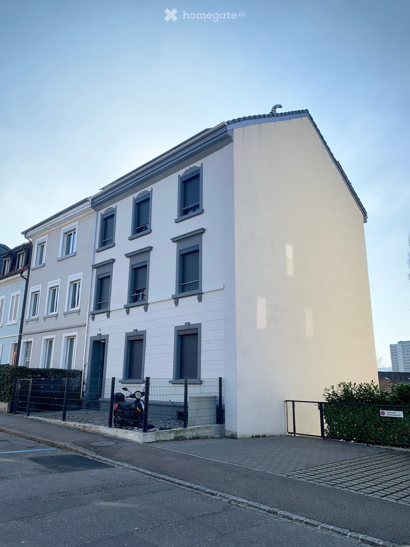 White building with multiple windows, multiple stories, small motorbike parked on the front sidewalk