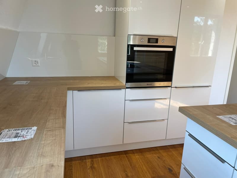 white cabinets, wooden countertops, integrated oven, white wall, outlet, and wooden floor