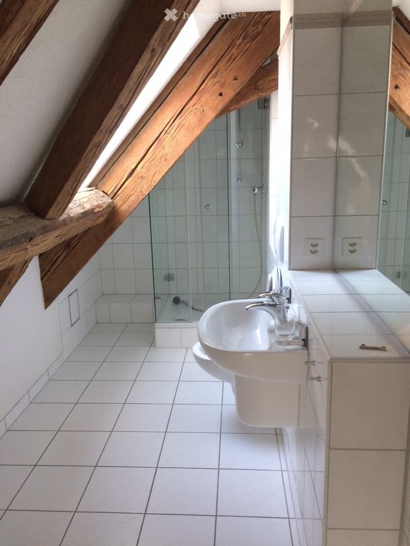 Bathroom with white tiles, glass shower, white sink, wooden beams