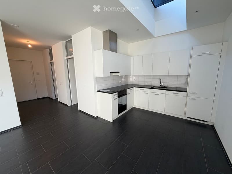 white cabinets, black floor, integrated appliances, skylight, kitchen area