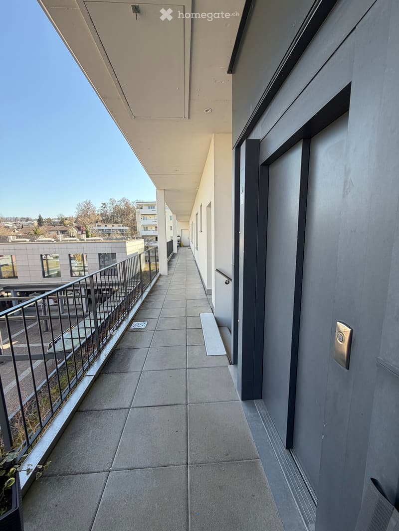 Balcony with fence, gray tile flooring, door to apartment on the right side