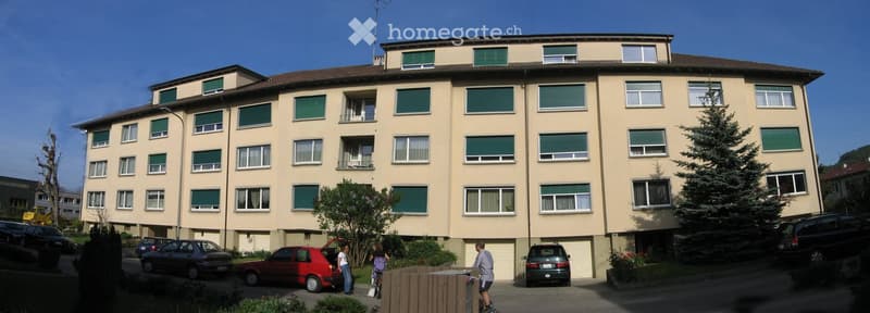 4 story apartment building, beige exterior, green shutters, 2 garages, 2 cars parked in front